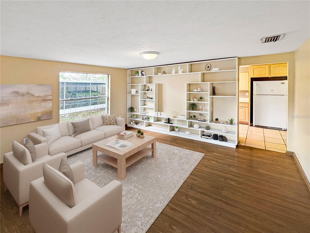 A living room features a large built-in shelving unit, light-colored furniture, and wood-look flooring — 1815 LOWRY AVENUE, LAKELAND, FL