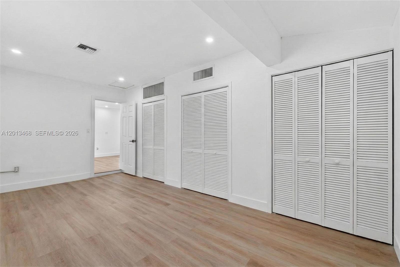 A room with white walls, light wood-look flooring, and two sets of louvered closet doors — 6621 Ficus Dr, Miramar FL 33023, MIRAMAR, FL