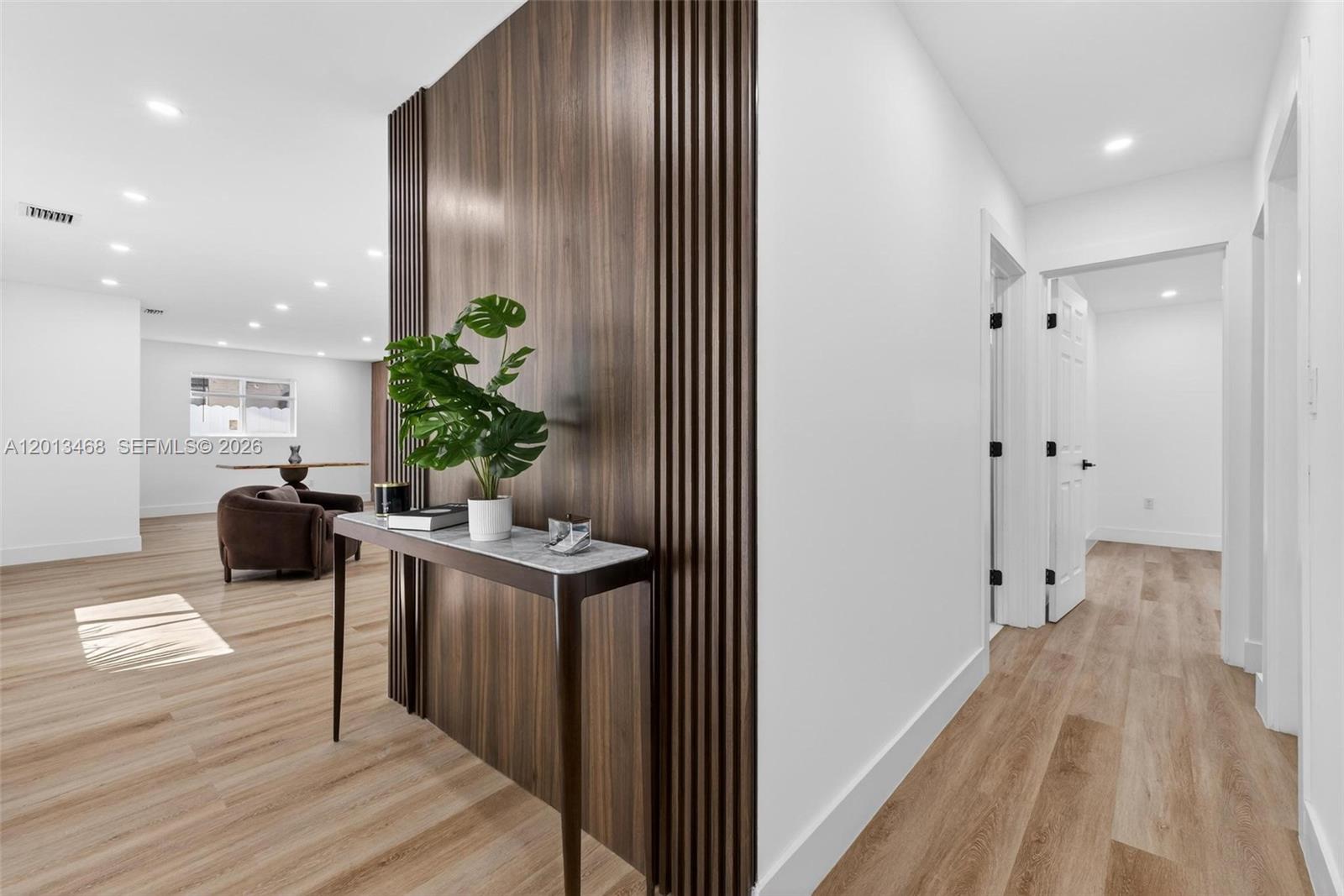 A modern entryway features a slatted wood accent wall, a marble-topped console table, and flooring — 6621 Ficus Dr, Miramar FL 33023, MIRAMAR, FL