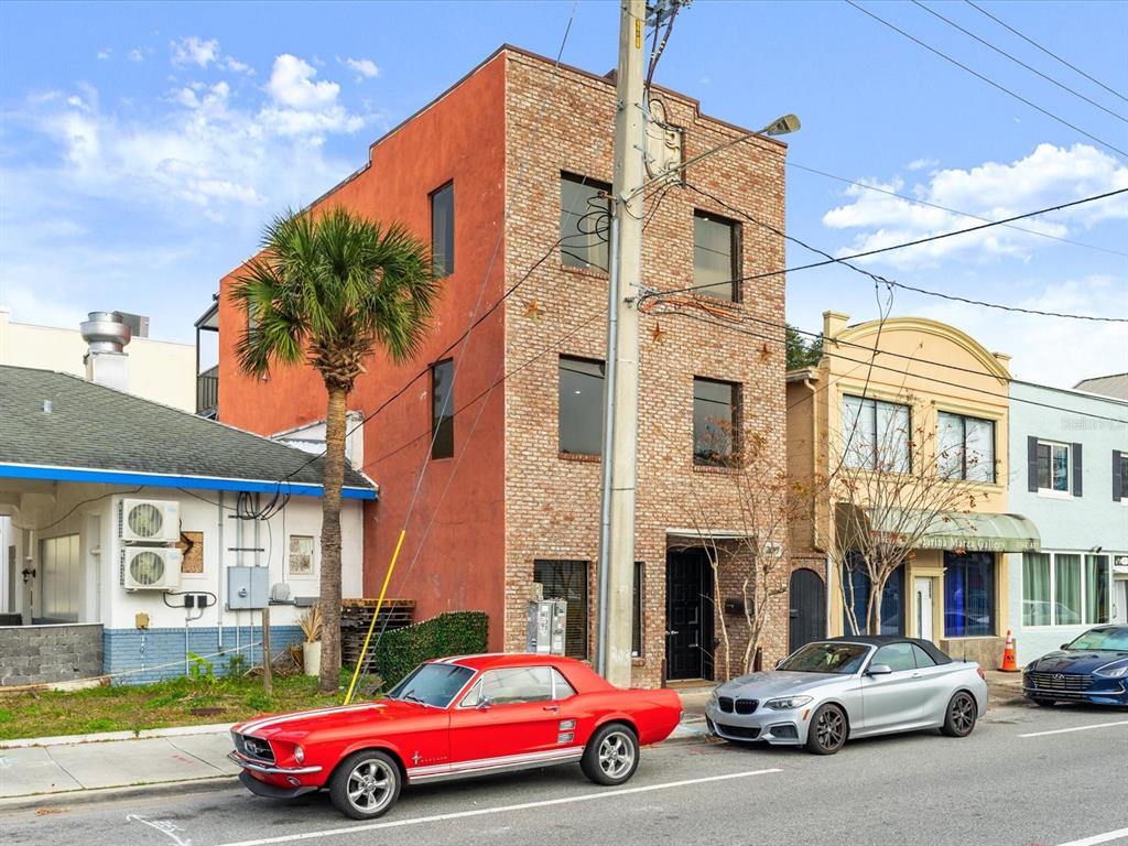 A three-story brick and stucco building stands on a street with parked cars — 307 S PALMETTO AVENUE, DAYTONA BEACH, FL