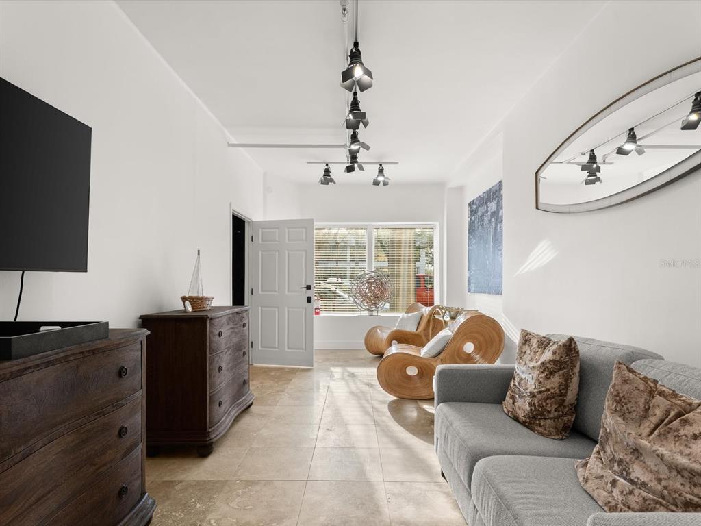 A living room features a grey sofa, wooden accent chairs, tile flooring, and track lighting — 307 S PALMETTO AVENUE, DAYTONA BEACH, FL