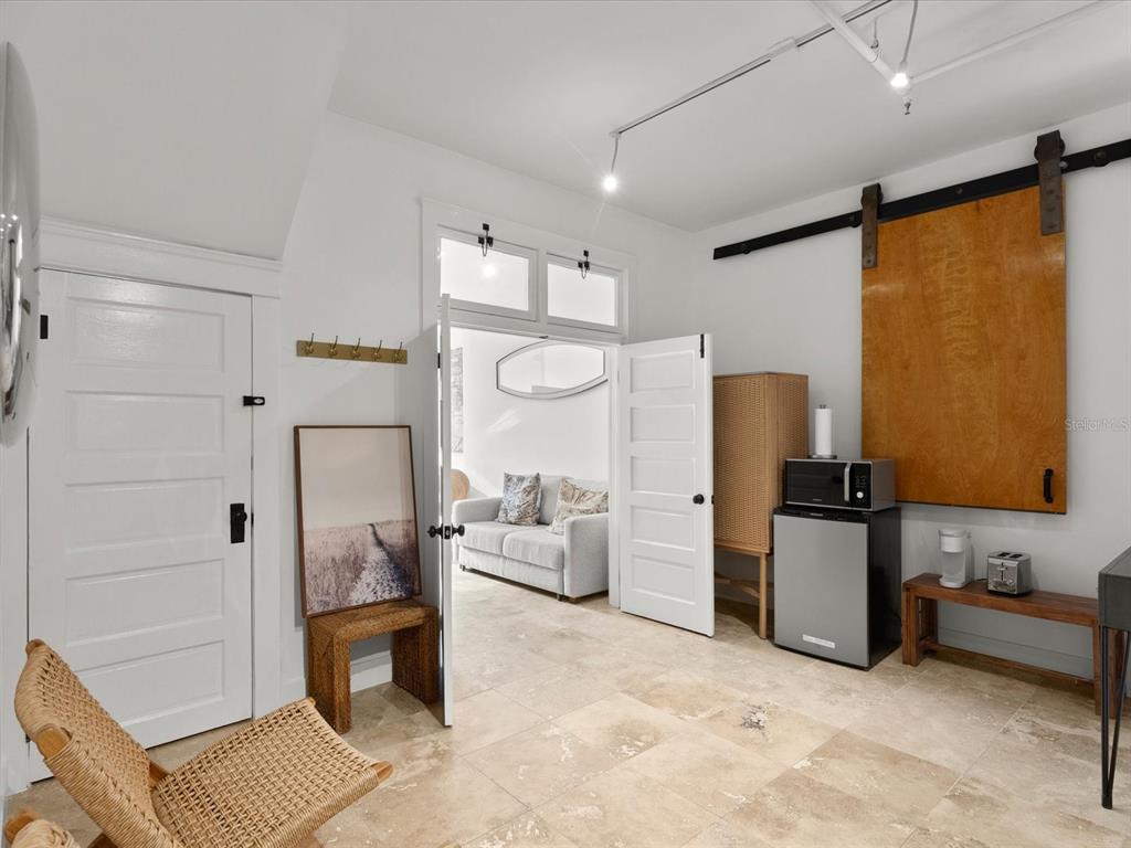 A room with tiled floors features a kitchenette area, a sliding barn door, and an entryway — 307 S PALMETTO AVENUE, DAYTONA BEACH, FL