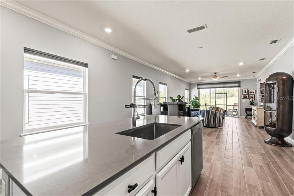 A kitchen island with a sink overlooks an open-concept living area with tile flooring — 907 STILLWATER BOULEVARD, ST JOHNS, FL