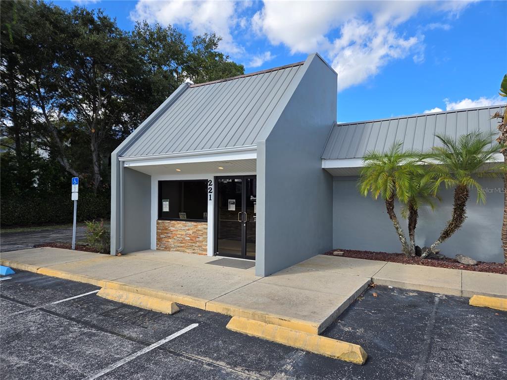 The exterior of a commercial building features a metal roof, stone accents, and a glass door — 221 W STATE ROAD 434, LONGWOOD, FL