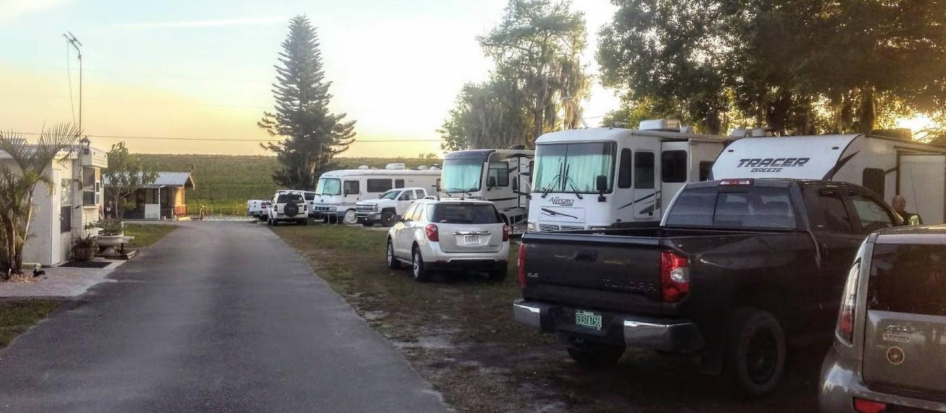 An outdoor view of a paved driveway lined with parked recreational vehicles and passenger cars — 4074 Hwy 441, Okeechobee FL 34971, OKEECHOBEE, FL
