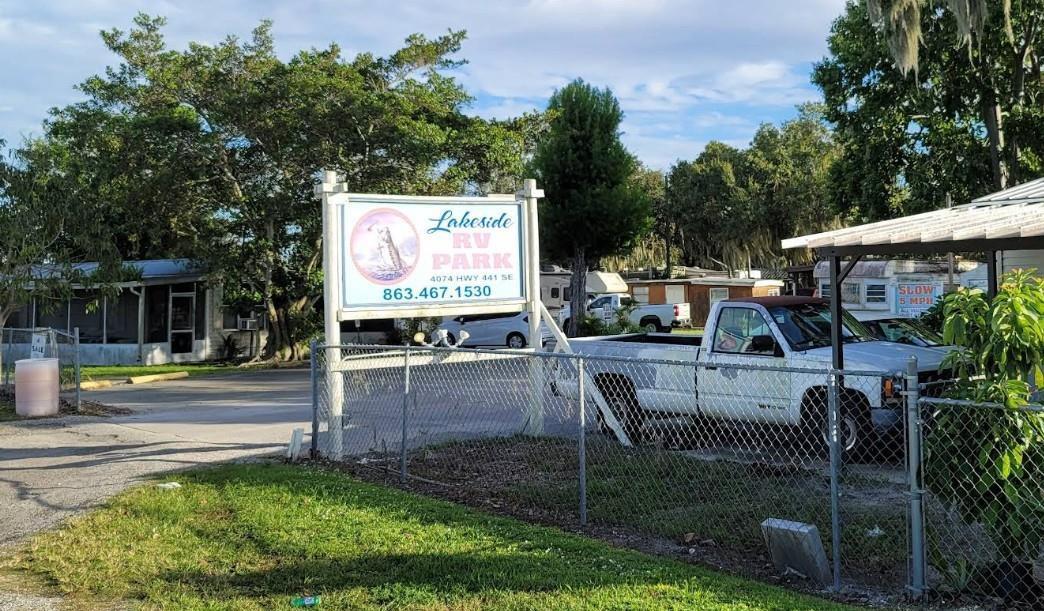 A sign for Lakeside RV Park stands behind a chain-link fence near a white truck — 4074 Hwy 441, Okeechobee FL 34971, OKEECHOBEE, FL