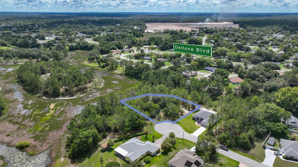 An aerial view shows a vacant, wooded residential lot outlined in blue within a neighborhood — VALLEY BROOK COURT, SPRING HILL, FL