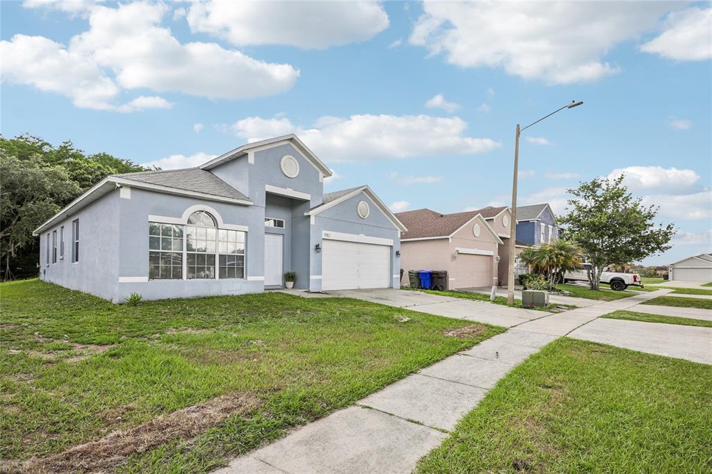 A light blue single-story house with a two-car garage sits on a suburban street — 1982 LOCUST BERRY DRIVE, KISSIMMEE, FL