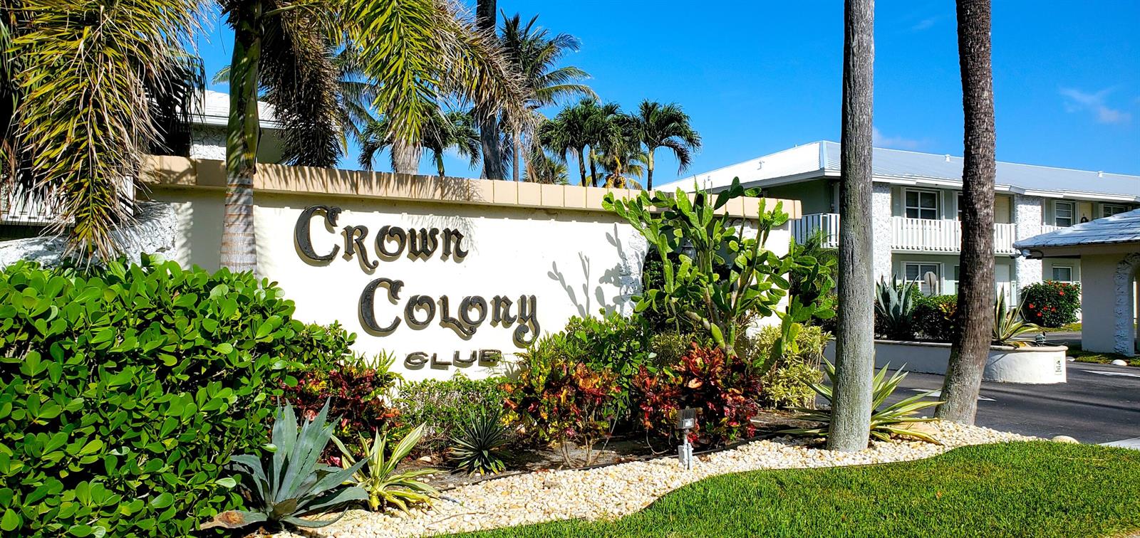 The exterior of the Crown Colony Club features a sign surrounded by tropical landscaping — 5530 N Ocean Boulevard # 106, Ocean Ridge FL 33435, OCEAN RIDGE, FL