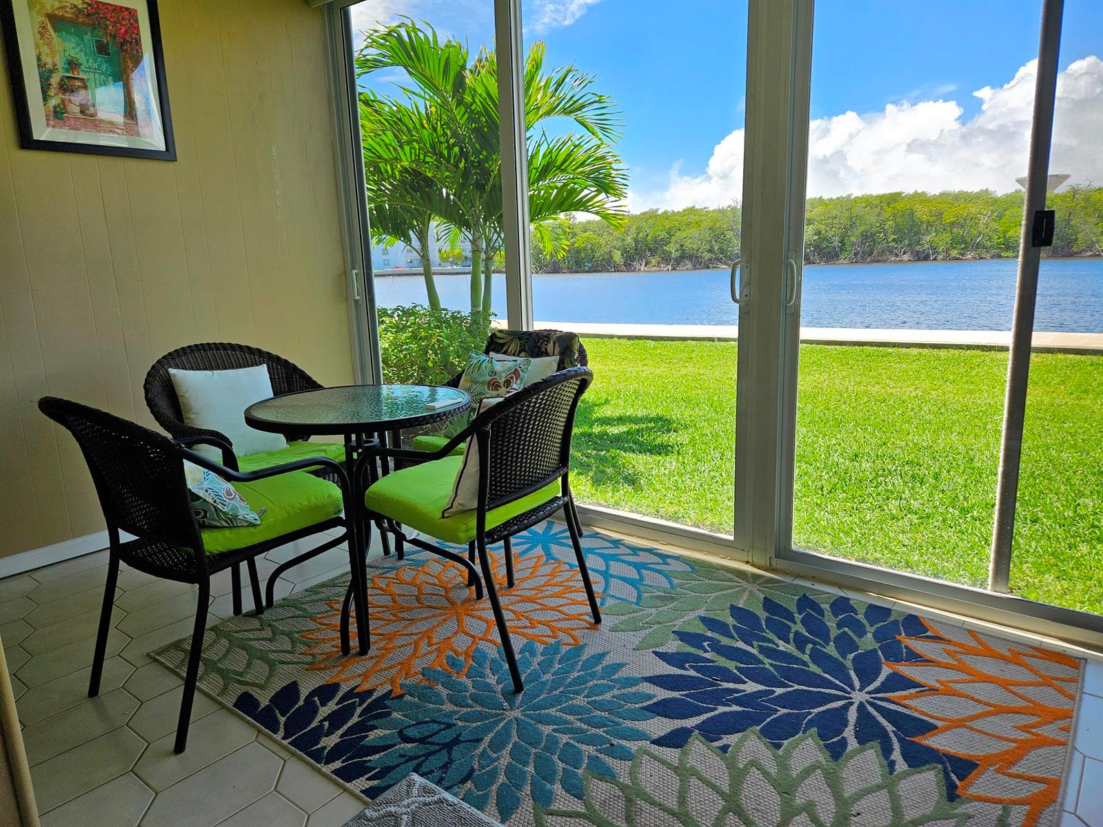 A sunroom features a small table and chairs set on a floral rug overlooking water — 5530 N Ocean Boulevard # 106, Ocean Ridge FL 33435, OCEAN RIDGE, FL