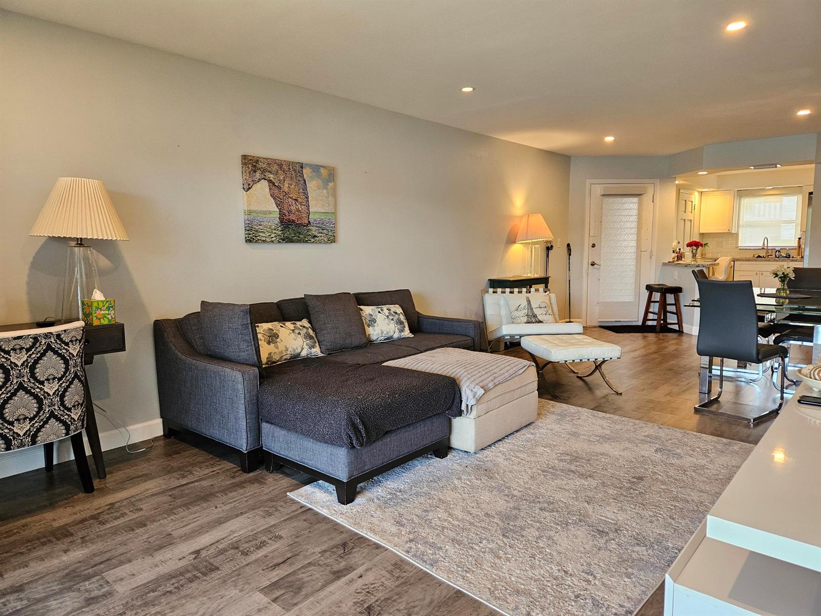 A living room features a gray sectional sofa, a patterned rug, and an open kitchen — 5530 N Ocean Boulevard # 106, Ocean Ridge FL 33435, OCEAN RIDGE, FL