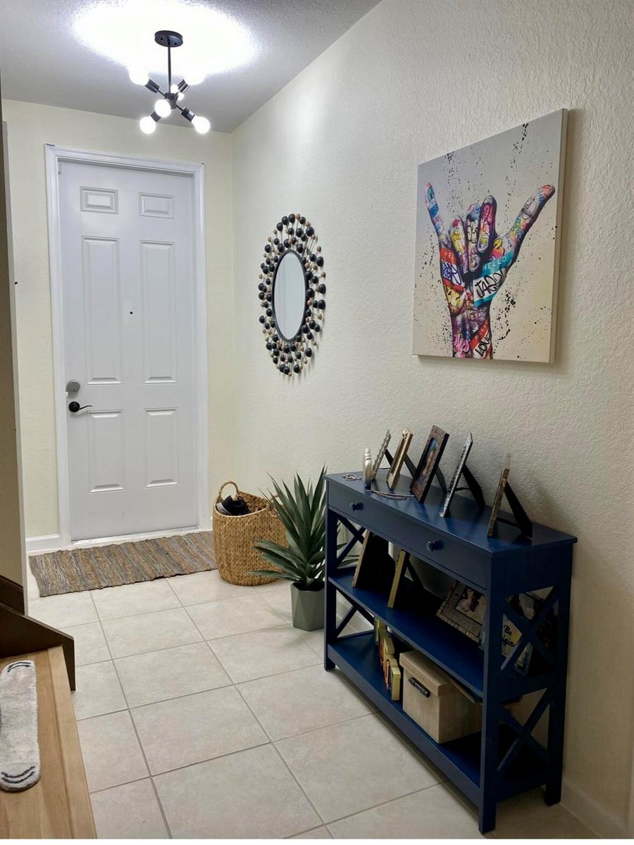 An entryway features a blue console table, a graffiti-style wall art piece, and a mirror — 2823 S Evergreen Circle, Boynton Beach FL 33426, BOYNTON BEACH, FL