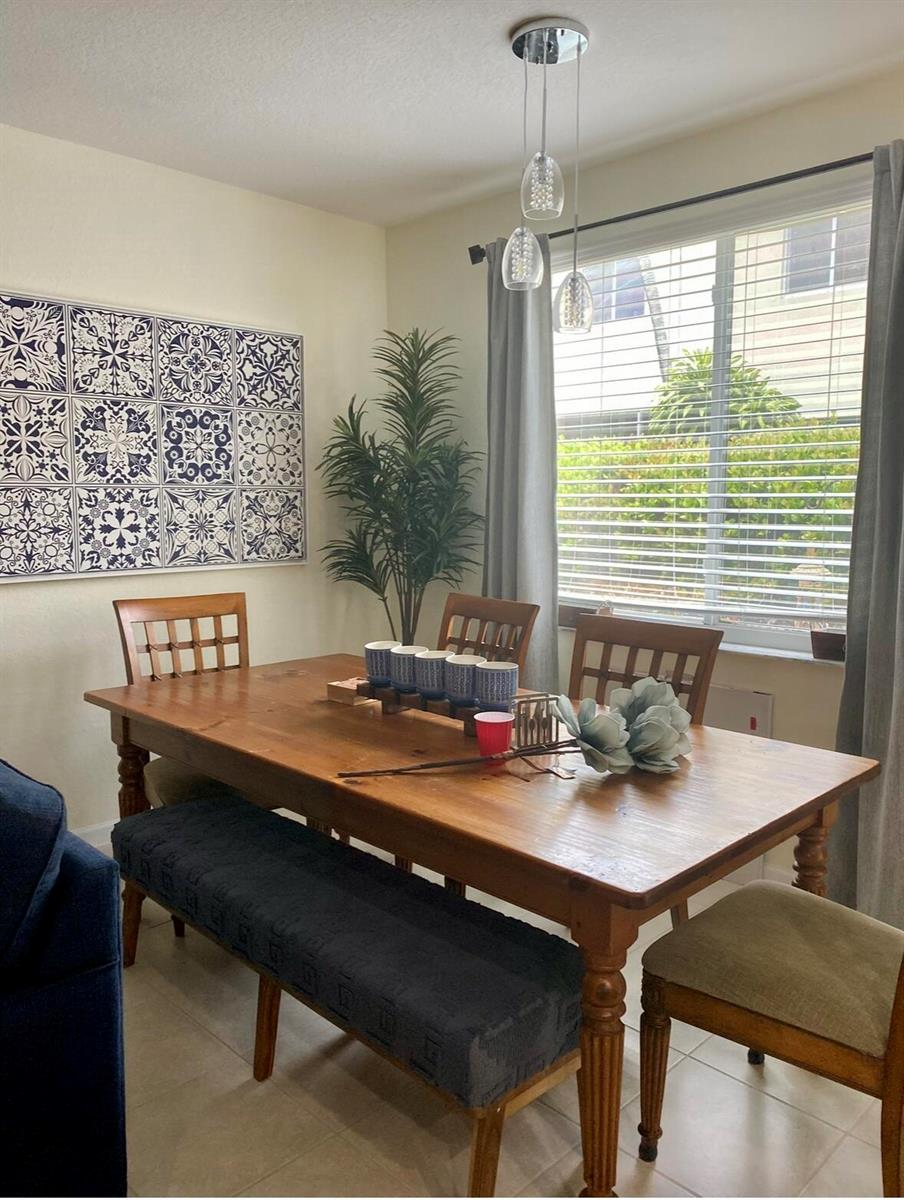 A dining room features a wooden table, a bench, chairs, and blue patterned wall art — 2823 S Evergreen Circle, Boynton Beach FL 33426, BOYNTON BEACH, FL