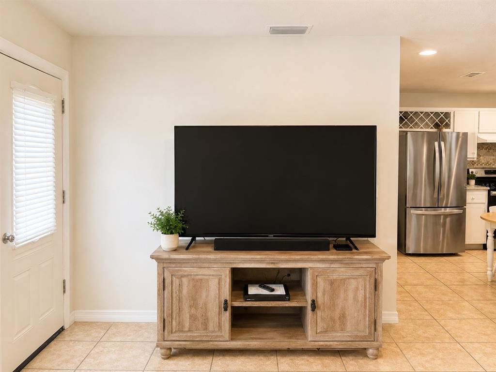 A television sits on a wooden media console in a room with tile flooring — 3430 TAMARIND DRIVE, EDGEWATER, FL