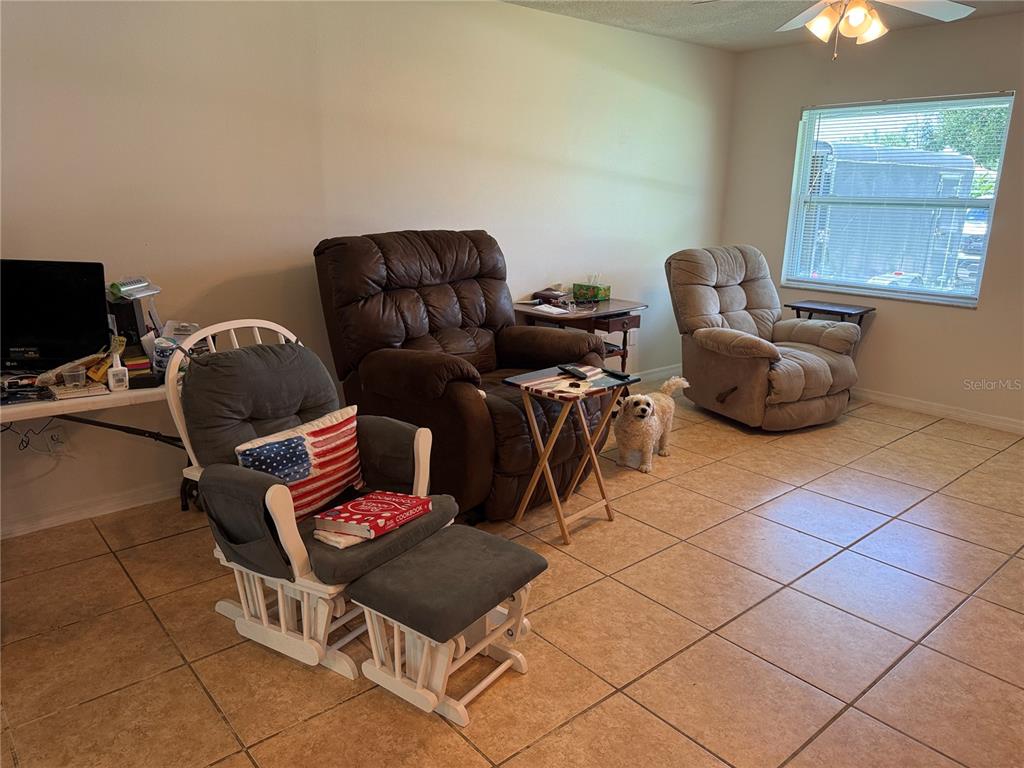 A living room features tiled floors, three armchairs, a small side table, and a dog — 3430 TAMARIND DRIVE, EDGEWATER, FL