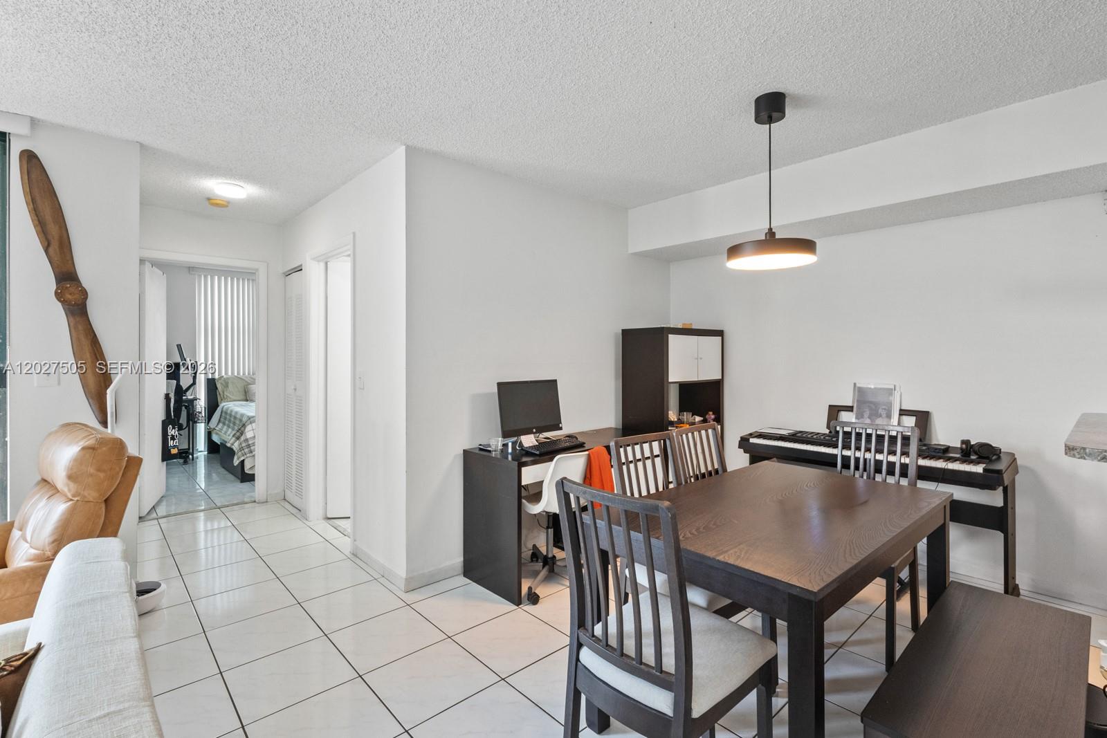 A dining area features a dark wood table, chairs, a desk, and a piano — 2075 SW 122nd Ave # 226, Miami FL 33175, MIAMI, FL
