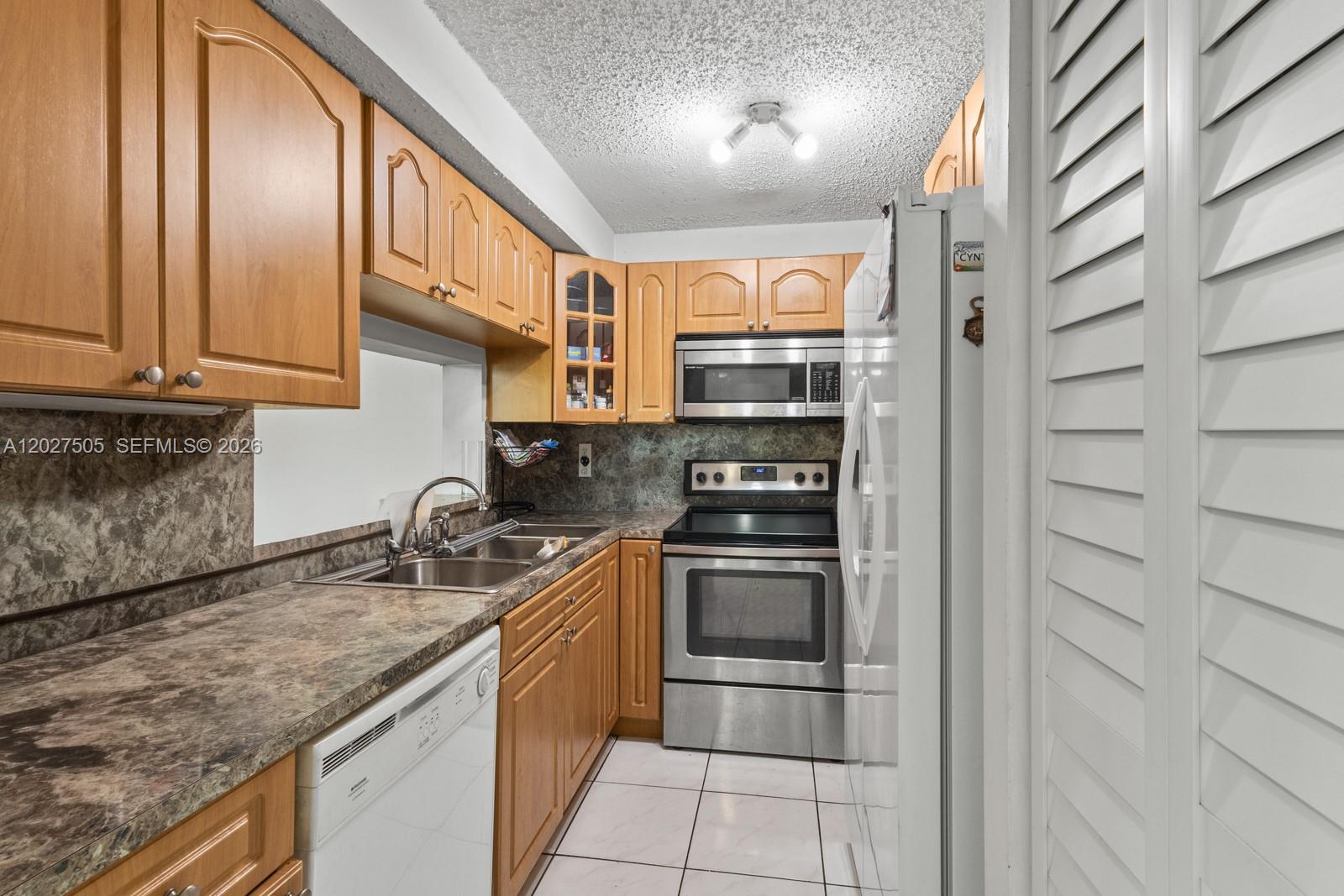 A kitchen features wood cabinets, stainless steel appliances, a double sink, and tiled flooring — 2075 SW 122nd Ave # 226, Miami FL 33175, MIAMI, FL