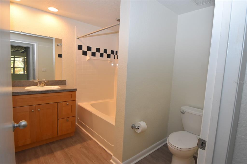 A bathroom features a wood vanity, a shower-tub combination with checkered tile, and a toilet — 2402 W AZEELE STREET UNIT 426, TAMPA, FL