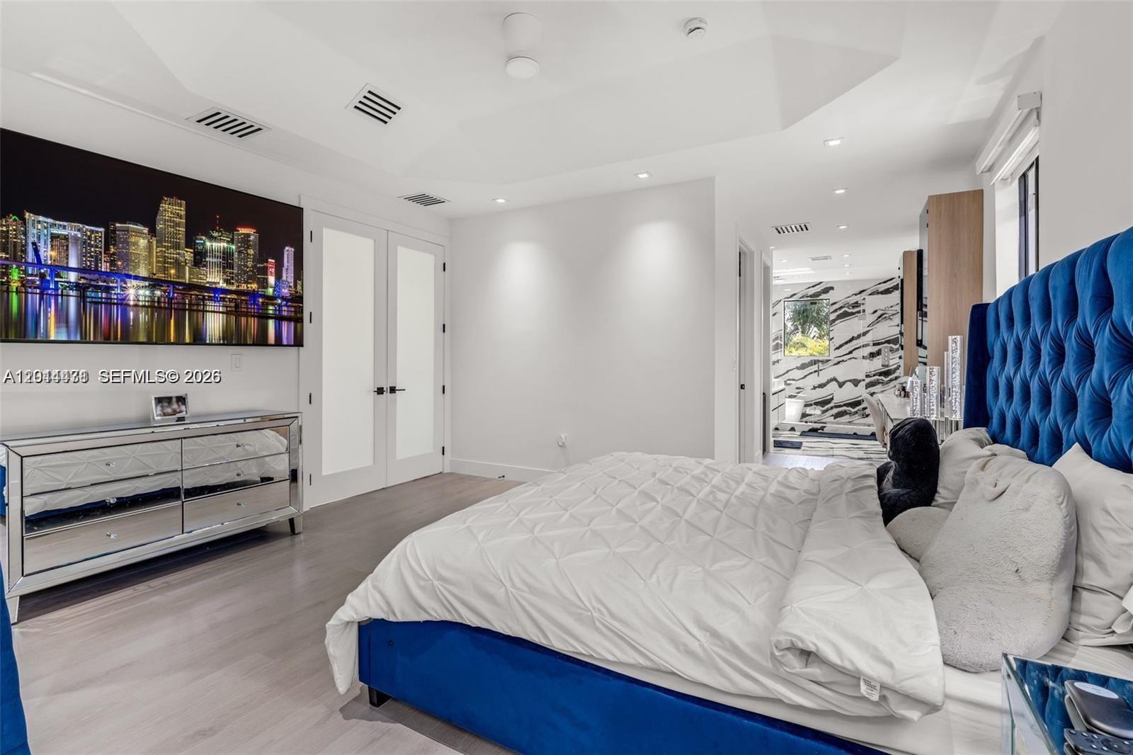 A bedroom features a blue tufted headboard, a mirrored dresser, and a wall-mounted television — 19246 SW 132nd Ave, Miami FL 33177, MIAMI, FL