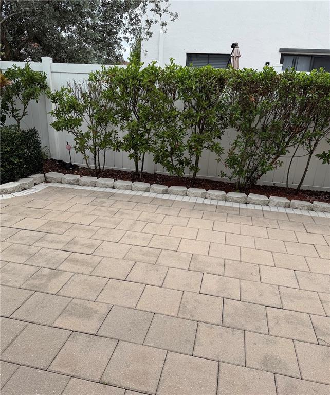 A paved patio sits in front of a white vinyl fence and a hedge — 10306 W 33RD LANE, HIALEAH, FL