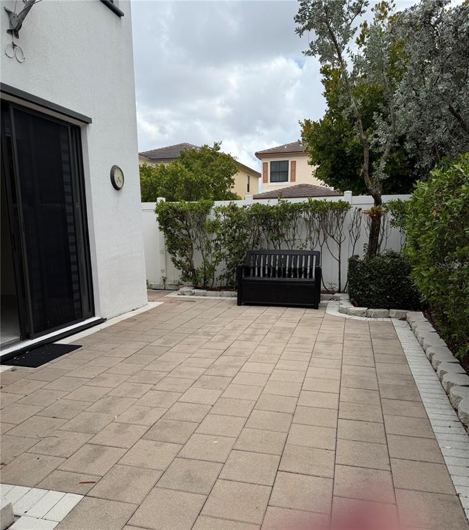 A paved patio features a black bench against a white fence and house wall — 10306 W 33RD LANE, HIALEAH, FL