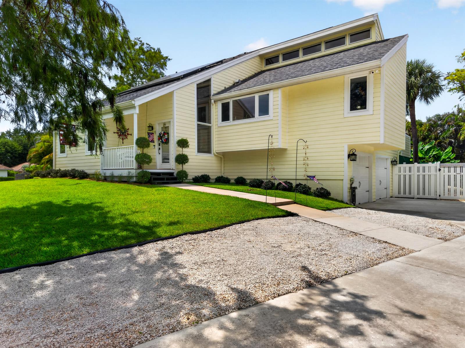A yellow two-story house with a gravel driveway, a front porch, and a garage — 13074 La Mirada Circle, Wellington FL 33414, WELLINGTON, FL