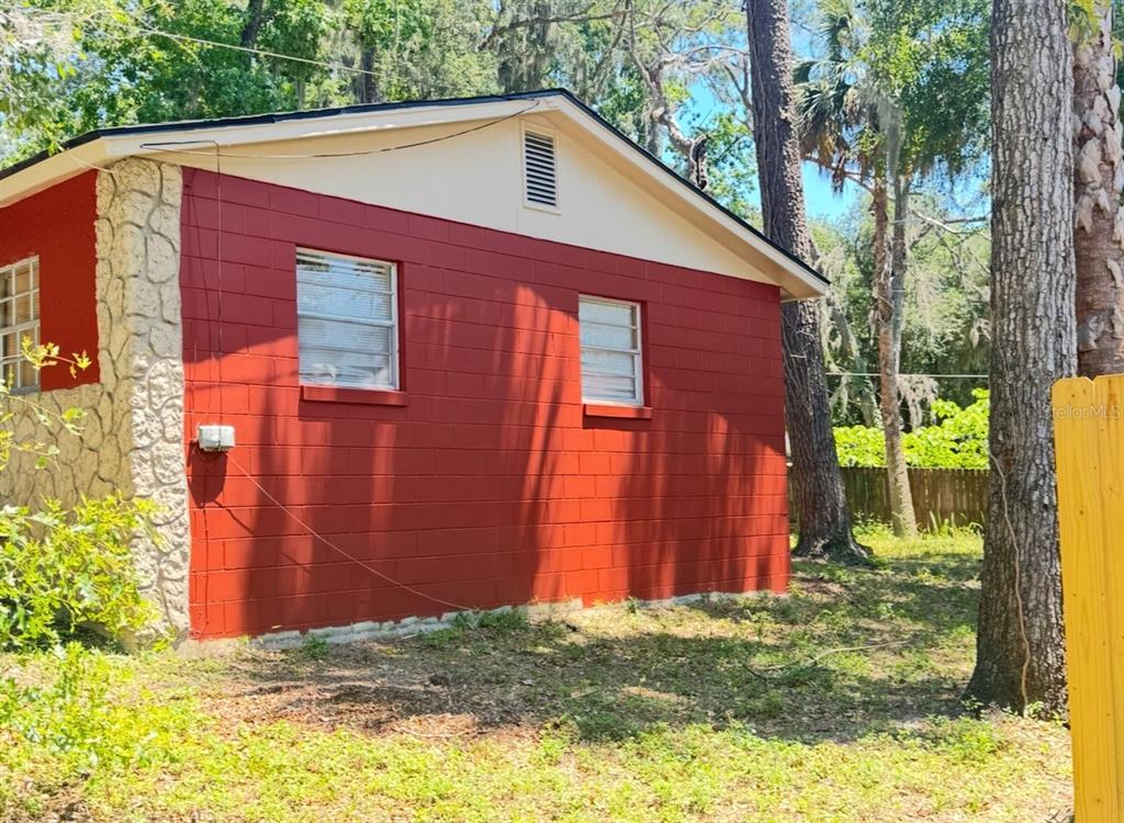 The exterior of a red concrete block house with a stone corner and two windows — 1338 NE 16TH STREET, OCALA, FL