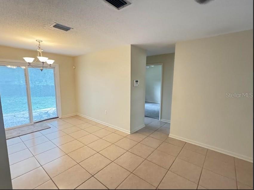 A dining area with tile flooring, a chandelier, and sliding glass doors leading outside — 1338 NE 16TH STREET, OCALA, FL