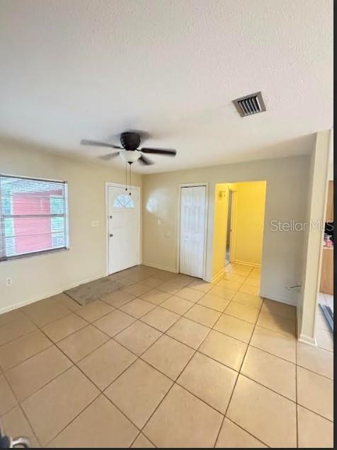 A room with beige tile flooring, a ceiling fan, a white door, and a window — 1338 NE 16TH STREET, OCALA, FL