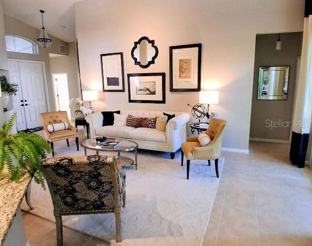 A living room features a white sofa, patterned armchair, and framed wall art — 6642 41ST STREET CIRCLE E, SARASOTA, FL