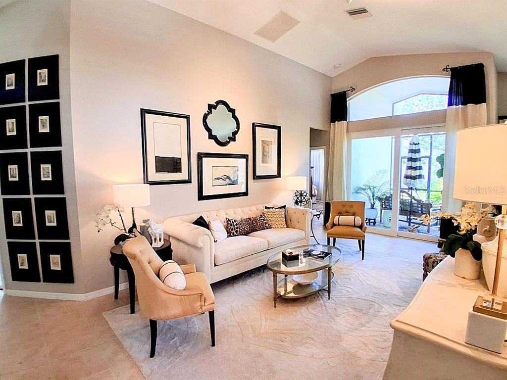 A living room features a beige sofa, two armchairs, a glass coffee table, and wall art — 6642 41ST STREET CIRCLE E, SARASOTA, FL