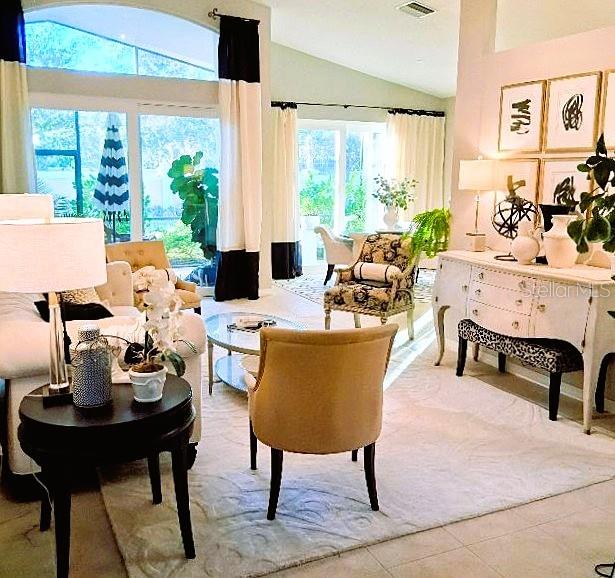 A bright living room features a white sofa, patterned armchair, and a white sideboard — 6642 41ST STREET CIRCLE E, SARASOTA, FL