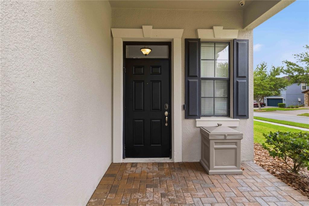 A front entryway with a black door, a window with shutters, and a stone-paved porch — 1001 OLIVETO VERDI COURT, BRANDON, FL
