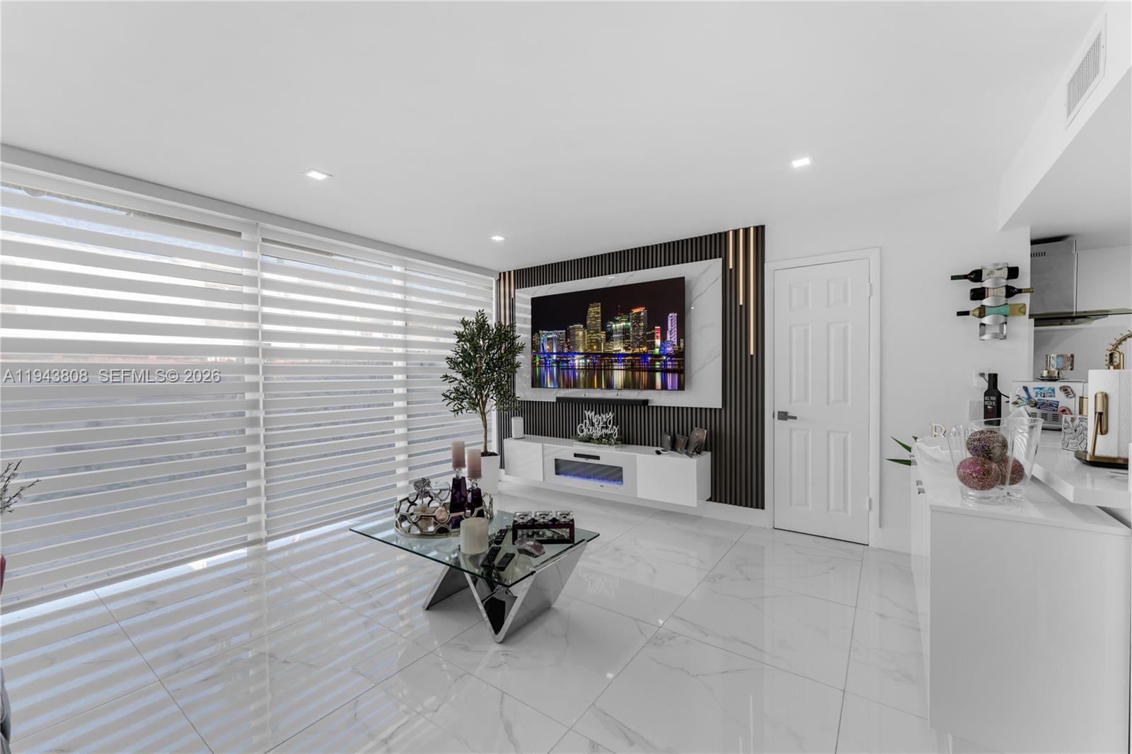 A modern living room features a wall-mounted television, a floating console, and marble-look flooring — 13835 SW 84th St # 503, Miami FL 33183, MIAMI, FL