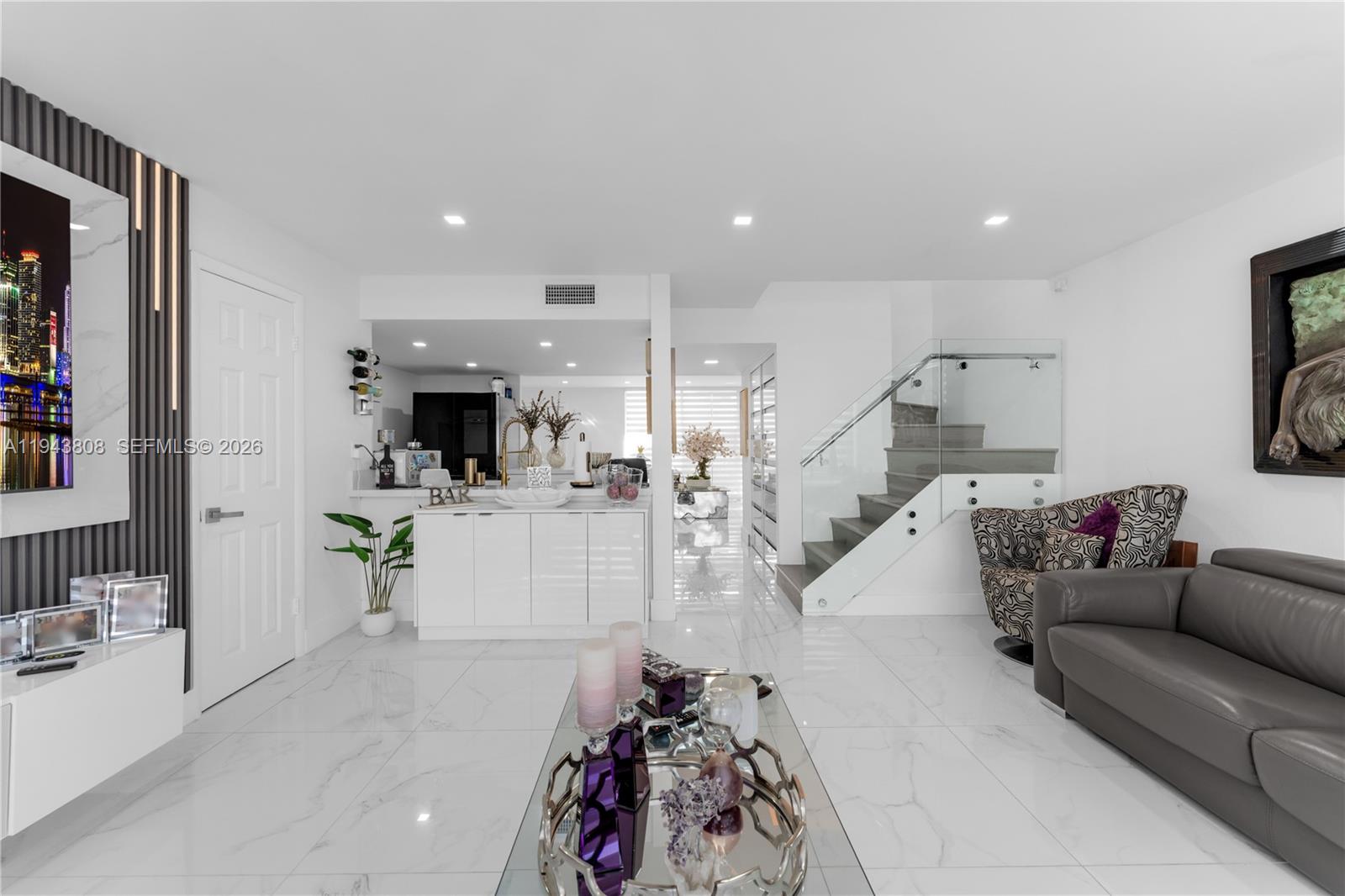 A modern living room features white tile floors, a glass-railed staircase, and a wet bar — 13835 SW 84th St # 503, Miami FL 33183, MIAMI, FL