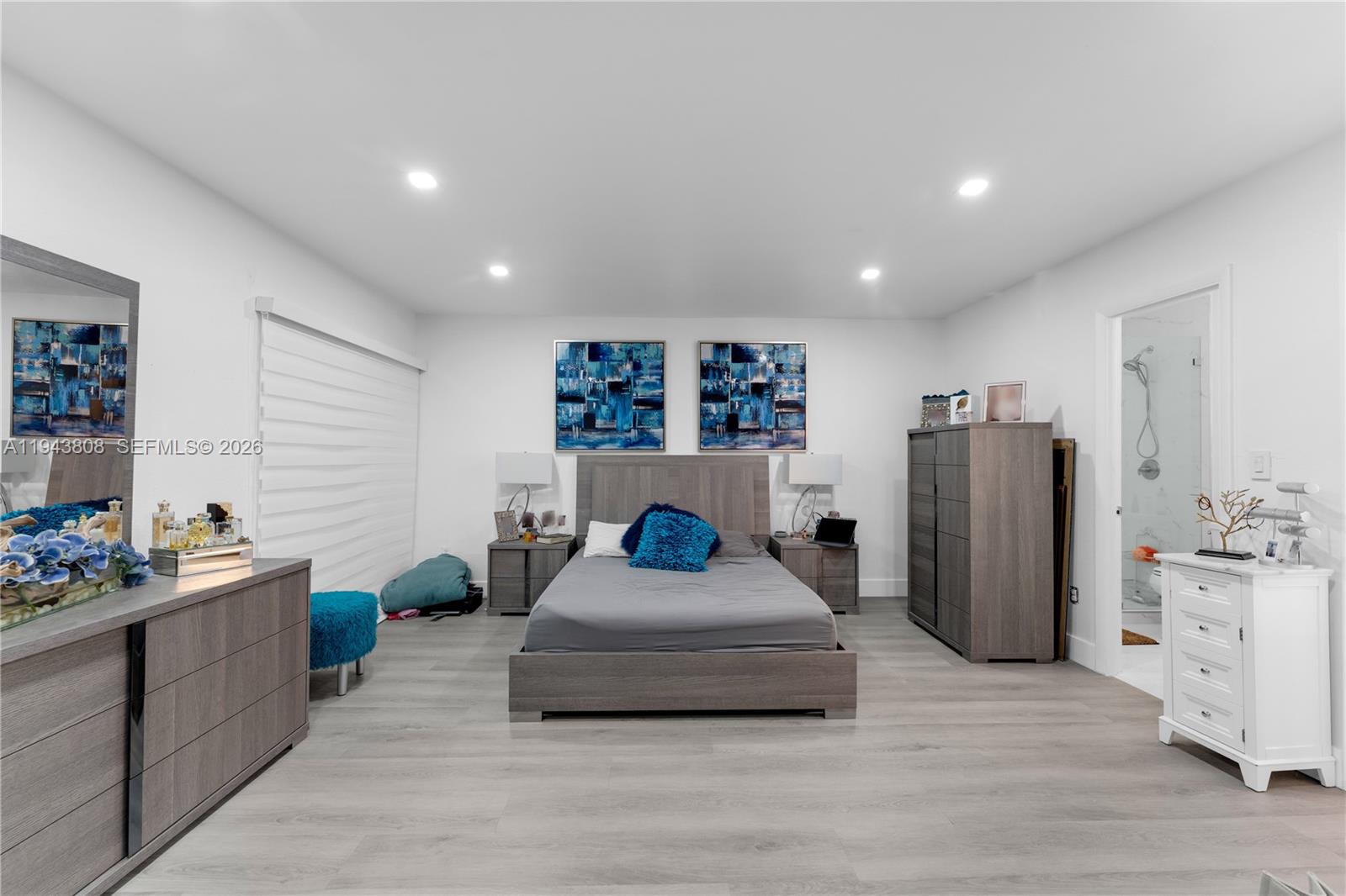 A bedroom features a gray bed, matching furniture, blue accent decor, and light wood flooring — 13835 SW 84th St # 503, Miami FL 33183, MIAMI, FL