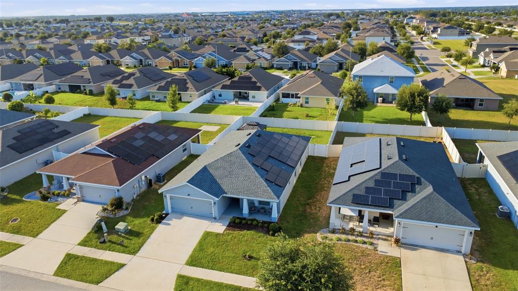 An aerial view shows several suburban houses with solar panels on their shingled roofs — 475 MONTICELLI DRIVE, HAINES CITY, FL