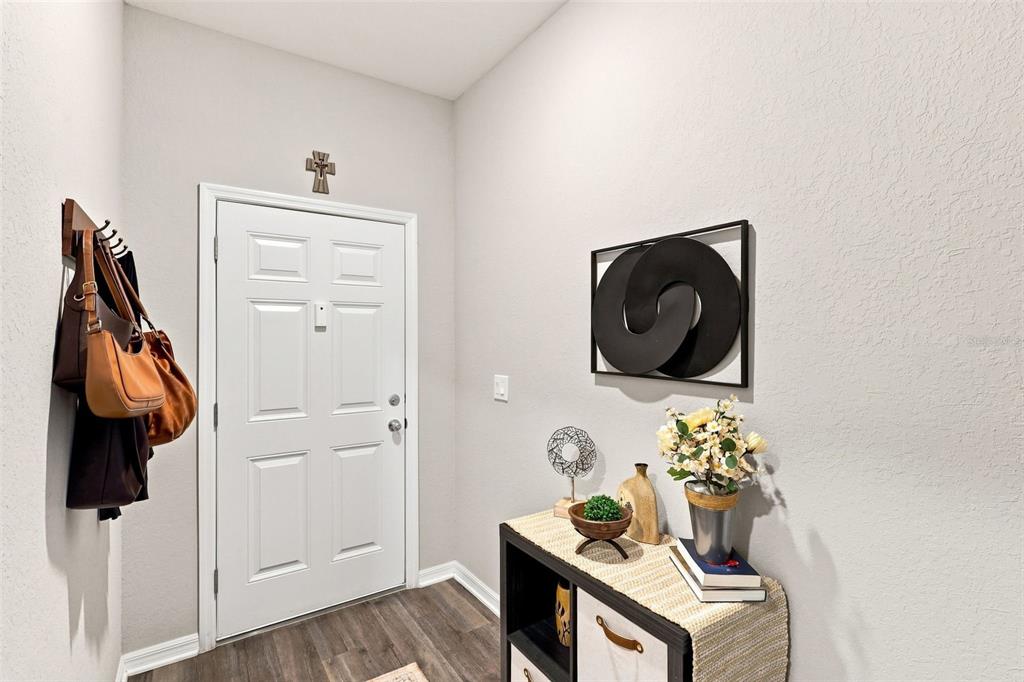 An entryway features a white door, a coat rack with bags, and a console table — 475 MONTICELLI DRIVE, HAINES CITY, FL