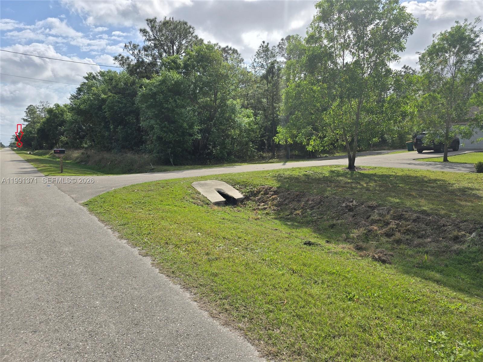A paved road runs alongside a grassy drainage ditch with a concrete culvert entrance — 2844 70th Ave NE, Naples FL 34120, NAPLES, FL