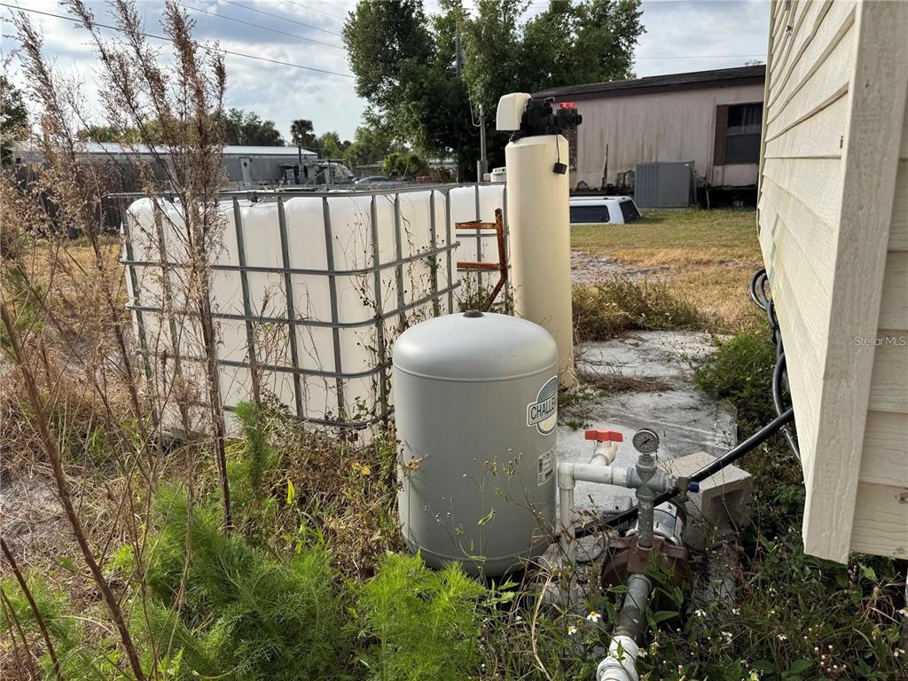 An outdoor water filtration system and storage tank sit next to the side of a house — 9308 MANDY STREET, PUNTA GORDA, FL