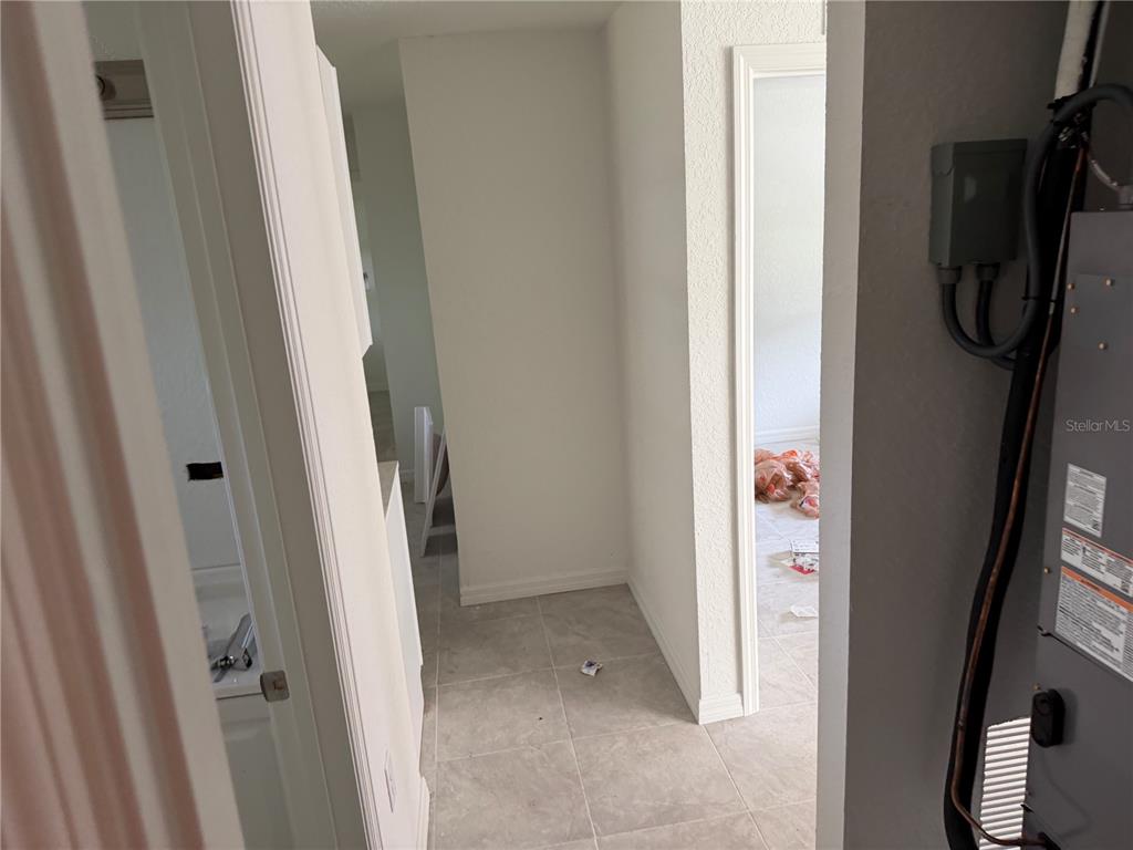 A hallway with light tile flooring leads to an open doorway and a utility closet — 6 S BARBOUR STREET, BEVERLY HILLS, FL