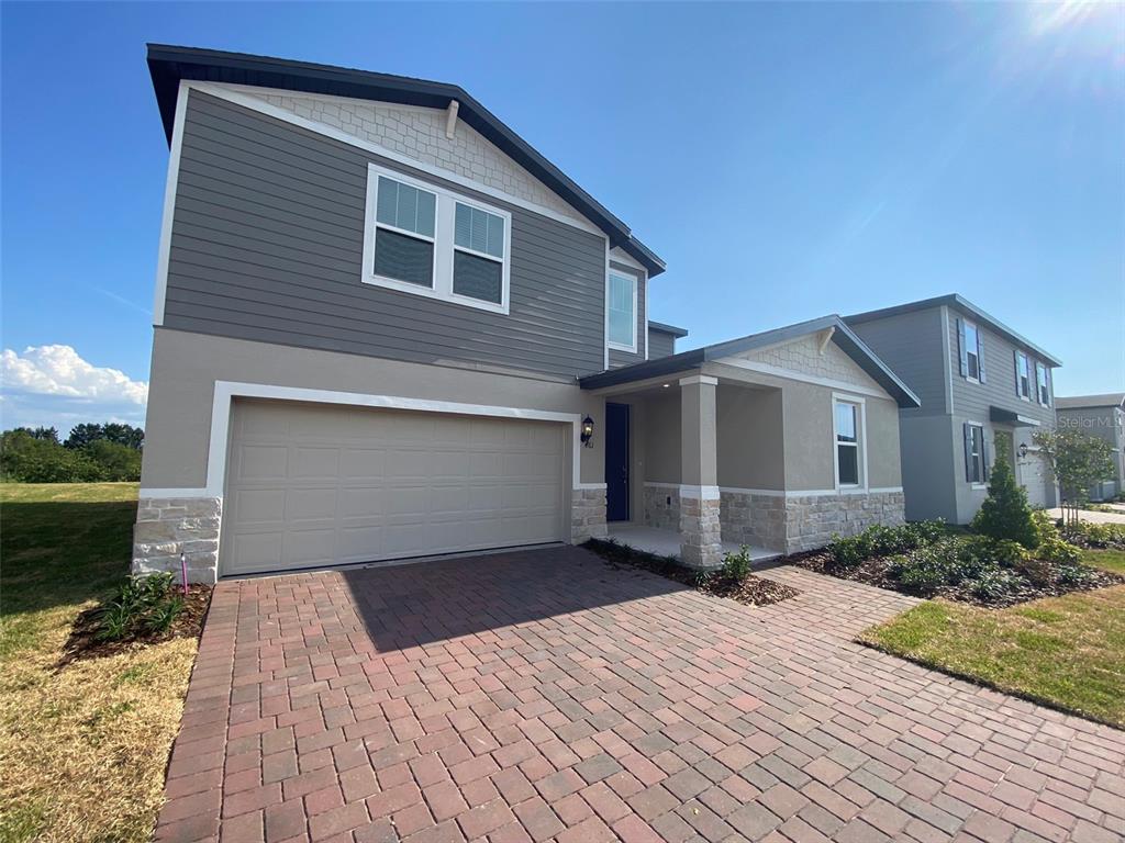 A two-story house features a brick paver driveway, a two-car garage, and stone accents — 461 WHISTLING DUCK TRAIL, ST CLOUD, FL