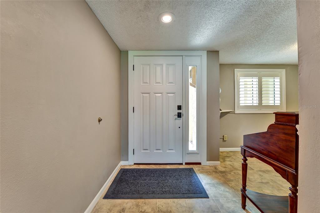 A hallway with wood floors leads to a living area featuring a glass console table — 8107 BARDMOOR PLACE UNIT 103, SEMINOLE, FL