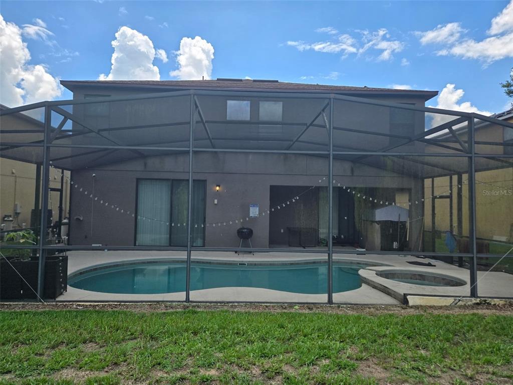 A backyard swimming pool and spa are enclosed by a screen cage behind a house — 1120 CYPRESS POINTE BOULEVARD, DAVENPORT, FL
