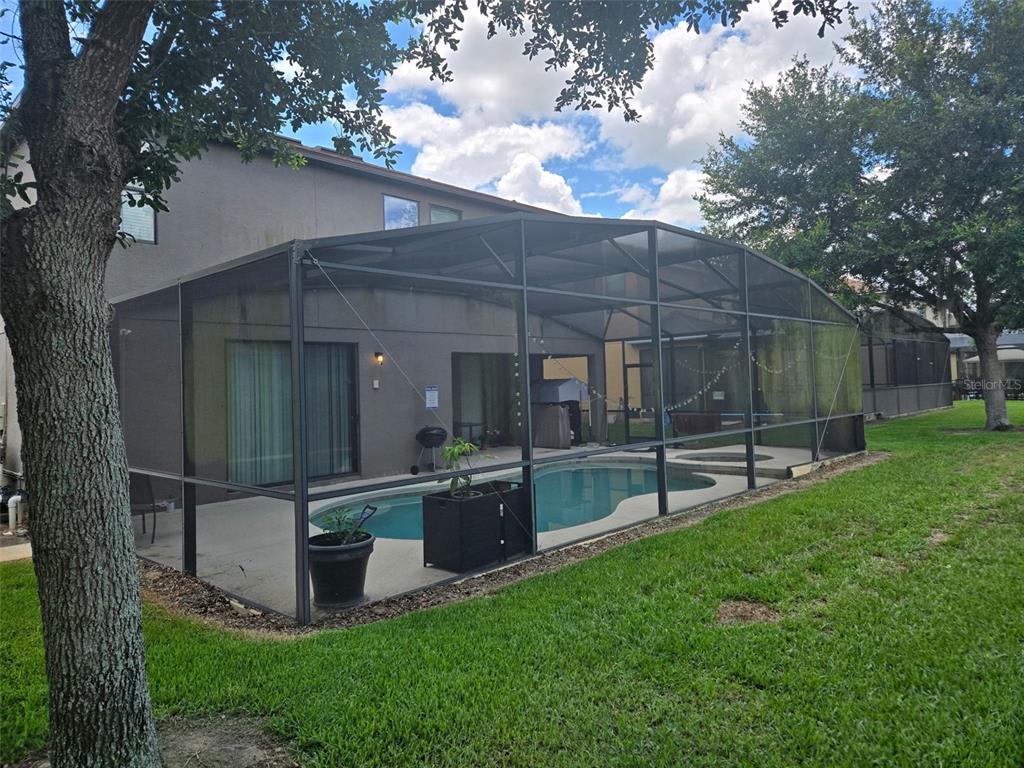A backyard features a swimming pool enclosed by a screened-in lanai attached to a house — 1120 CYPRESS POINTE BOULEVARD, DAVENPORT, FL