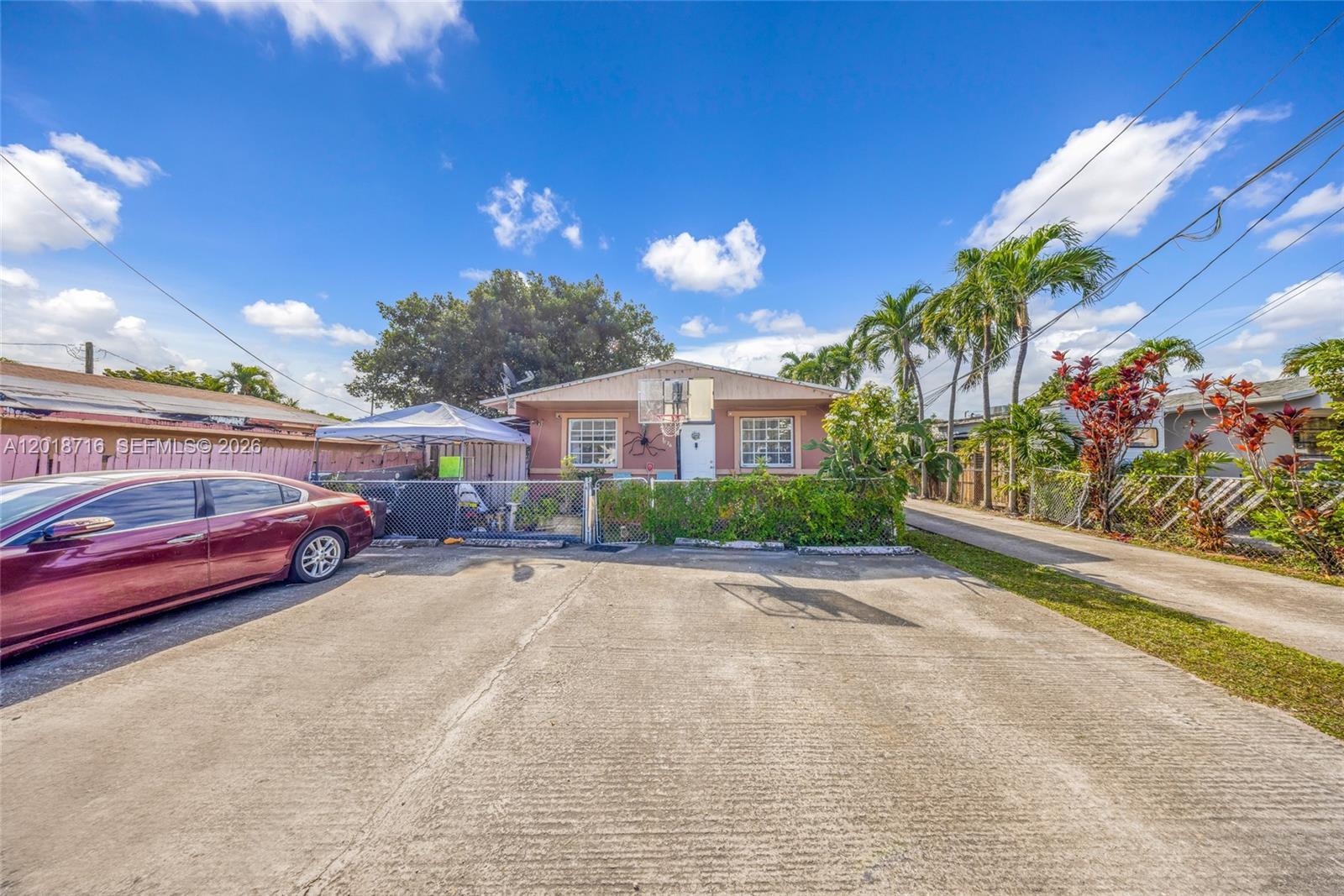 A single-story house with a concrete driveway, a chain-link fence, and palm trees — 3126 NW 28th St, Miami FL 33142, MIAMI, FL