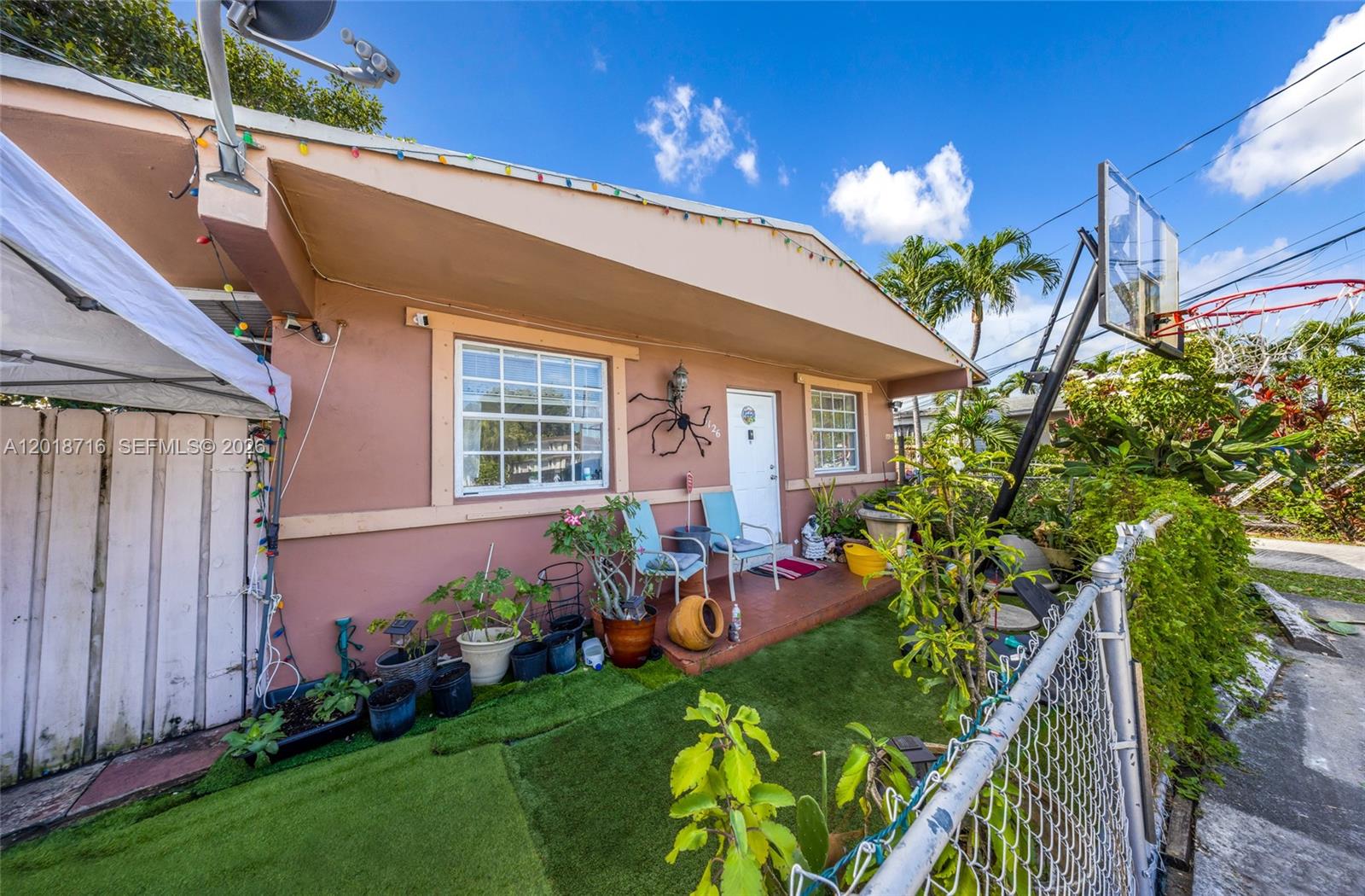 The exterior of a peach-colored house features a small porch, artificial turf, and a basketball hoop — 3126 NW 28th St, Miami FL 33142, MIAMI, FL