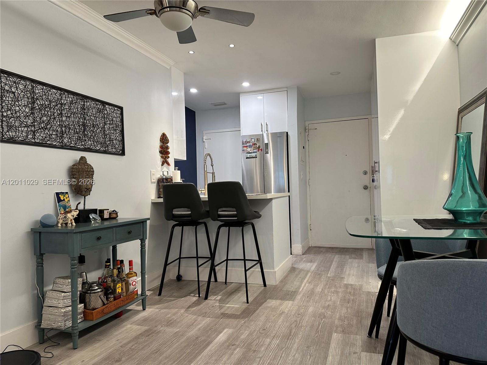 A kitchen with a breakfast bar and stools opens into a dining and living area — 1130 11th St # 4E, Miami Beach FL 33139, MIAMI BEACH, FL