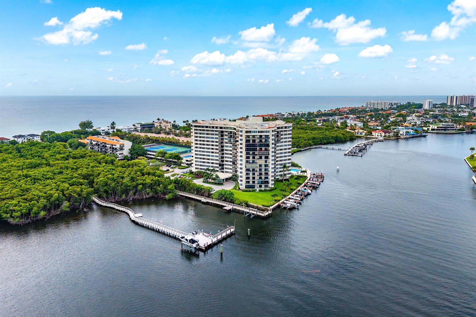 An aerial view shows a high-rise residential building surrounded by water, mangroves, and boat docks — 3912 S Ocean Boulevard # 612, Highland Beach FL 33487, HIGHLAND BEACH, FL