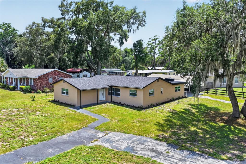 A tan, single-story house with a dark shingled roof sits on a grassy lot — 708 CINDY AVENUE, FRUITLAND PARK, FL